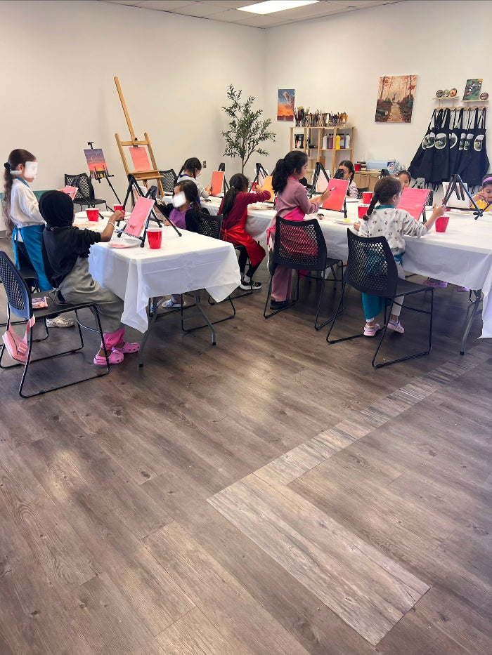 Art class in progress with students at tables with art supplies.
